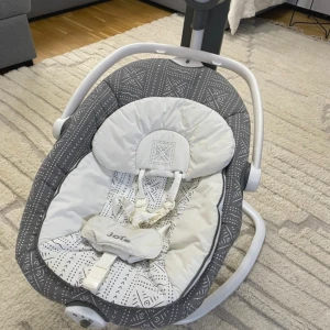 Joie Sansa 2-in-1 Baby Swing - Joie Sansa 2-in-1 babysitter och gunga i fint skick. Mjuk, mönstrad sits med säkerhetssele, flera gungfunktioner och kontrollpanel för musik och rörelse. Passar perfekt för små barn. Inga synliga defekter eller slitage.