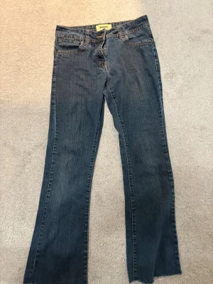 Blå bootcut jeans - Säljer ett par blå bootcut jeans med fina  broderade fickor. Jeansen passar bra på mig som är 160 cm lång. 