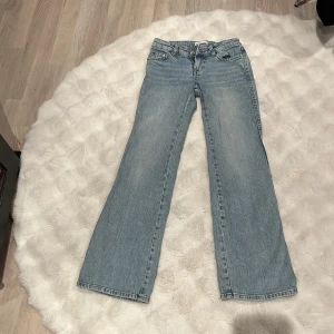 Perfekt ljusblå bootcut jeans strl 32 - Snygga ljusblå jeans från Perfect Jeans i storlek 32. Modellen har klassisk femficksdesign, låg midja och bootcut-ben som ger en cool siluett. Jeansen är tillverkade i mjukt denim och har knappar och dragkedja framtill.