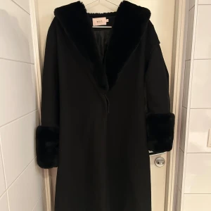 Svart kappa med päls - Svart kappa med päls från NELLY , väldigt fin kappa som går in vid midjan när man stänger den. Kan sänka pris vid snabb affär 