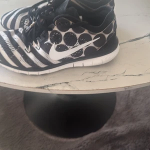 Nike svartvita sneakers med mönster - Unika Nike sneakers med svartvita ränder och stora prickar. Snyggt mönstrad mesh-ovandel, vit sula och klassisk Nike-logga på sidan. Skorna har snörning och platt sula, perfekt för dig som gillar att sticka ut med din stil.