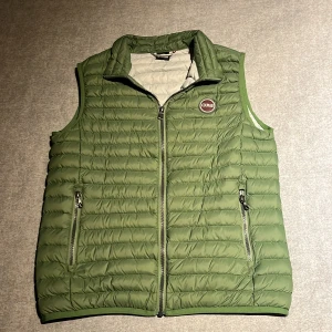 Grön dunväst från Colmar - Snygg grön dunväst från Colmar med quiltad design och två praktiska fickor med dragkedja. Västen har en hög krage och logotyp på bröstet. Perfekt att slänga över en hoodie för extra värme. Stängs med dragkedja framtill.