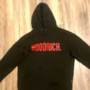Svart hoodie från Hoodrich med röd logga - Svart hoodie från Hoodrich med stor röd logotyp på bröstet. 