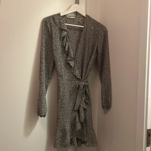 Grön omlottklänning från only.  - Långärmad klänning, volangdetaljer längs kanten och knyt i midjan. Stl 34.