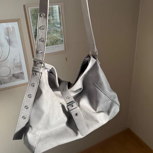 Grå axelväska med dragkedja - Nästan aldrig använd, ser helt ny och fräsch ut. Funkar perfekt till en vanlig dag, Inte för liten utan får plats med allt du behöver. Jätte snygg!!