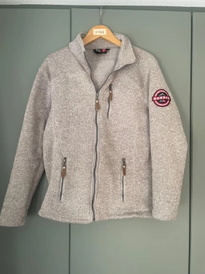 Fleece kofta/jacka - Säljer en grå/beige fleece kofta/jacka från Border Norwegian Design. Mycket bra skick och väldigt varm och mysig perfekt för vintern. 