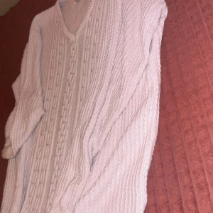 Ljusbeige stickad tröja från Stuts - Säljer en mysig ljusbeige stickad tröja från Stuts med snyggt flätmönster framtill och v-ringad hals. Tröjan har långa ärmar och ribbade muddar, perfekt för kyliga dagar. Passar dig som gillar klassisk och chill stil.