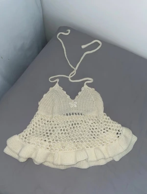 Stickad cremefärgad linnetopp SHEIN - Supersöt cremefärgad stickad linnetopp från SHEIN med knyt i nacken, volangkant och öppet virkat mönster. Toppen har dekorativa snäckor längs bysten och en snäcka formad som en blomma framtill. Perfekt för sommarens alla tillfällen! Aldrig använd nypris 159