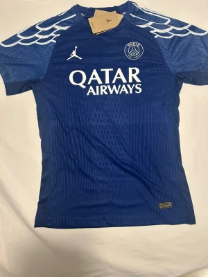 psg Tröja  - Bilderna visar en blå PSG fotbollströja med Vitinha 17 på ryggen. Nike, Jordan, med Qatar Airways som sponsor. 