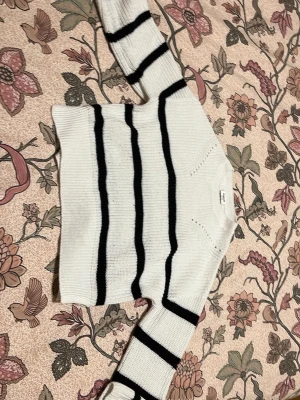 Vit och svart randig stickad tröja Kappahl - Säljer en vit stickad tröja från Kappahl med svarta horisontella ränder. Tröjan har lång ärm och en klassisk rund halsringning. Perfekt för dig som gillar en enkel men snygg look med lite sailor-vibe.