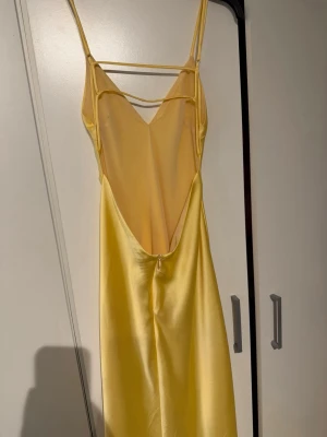 Gul långklänning med öppen rygg - Säljer en gul långklänning i satin från Zara med öppen rygg. Klänningen är använd 1 gång och är i mycket fint skick🫶🏽