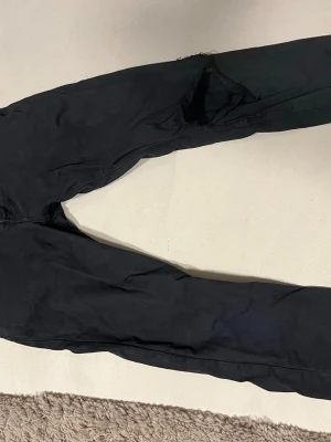 Svarta skinny jeans från Armani - Svarta jeans från Armani med klassisk femficksdesign och metallknapp framtill. Byxorna har smal passform och är tillverkade i ett mjukt bomullsmaterial med lite stretch. Snyggt broderad logga på fickan och dragkedja i gylfen. Perfekt för dig som gillar stilrena och slimfit jenas nypris på 3500kr.