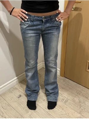 Lågmidjade jeans - Säljer ett par klassiska blå Levi's jeans med bootcut passform. Jeansen har låg midja, fem fickor och snygga slitningar framtill. Perfekta för dig som gillar en avslappnad och tidlös stil. Materialet är slitstark denim i bomull.