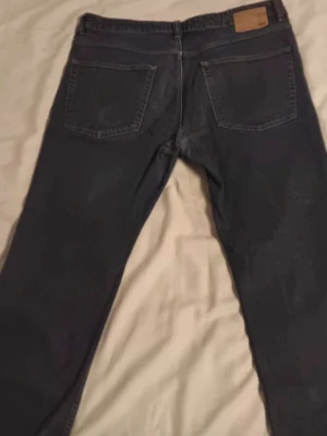 Levi's 501 mörkblå jeans straight fit - Mörkblå Levi's 501 jeans med klassisk straight fit och fem fickor. Jeansen har en snygg tvätt och detaljer som synliga sömmar och läderpatch bak i midjan. Materialet är robust jeans och passformen är normal, perfekt för en chill och stilren look.
