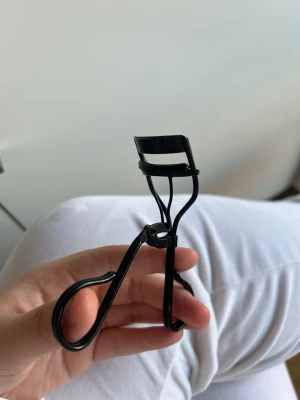 Svart ögonfransböjare från H&M - Säljer en klassisk svart ögonfransböjare från H&M. Den har en stilren design i metall med bekväma handtag och en mjuk gummilist för att skydda fransarna. Perfekt för att få till den där snygga böjen på fransarna snabbt och enkelt.