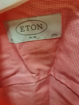 Rutig rosa skjorta från Eton slim - Snygg rosa skjorta från Eton i slim fit med diskret rutigt mönster. Skjortan har klassisk krage, vita knappar och lång ärm. Materialet är mjuk bomull och insidan av knappslån har en färgglad detalj. Perfekt för dig som gillar stilrena plagg med lite edge.