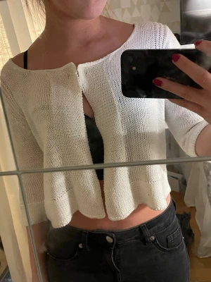 Vit stickad kofta från Gina Tricot - Säljer en vit stickad kofta från Gina Tricot med trekvartsärm och öppen framtill. Koftan har en croppad passform.💕