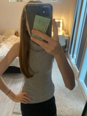 Grå ribbad polotopp från Lindex - Säljer en grå ärmlös polotopp från Lindex i storlek S. Toppen är ribbad och har en hög polokrage som ger en snygg och clean look. Perfekt till jul eller skolan eftersom den är lätt att både klä upp och ner!