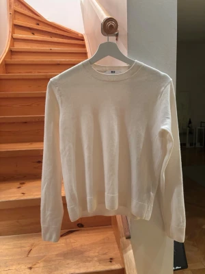 Creme färgad/ vit cashmere tröja - Säljer en oanvänd stilren creme/ vit färgad cashmere tröja från Uniqlo i storlek M. Perfekt för lager-på-lager och enkel att matcha med jeans eller chinos. Nypris 1299kr.