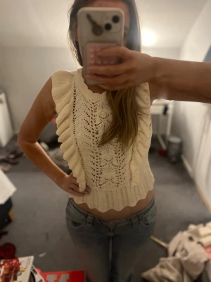 Vit stickad ärmlös topp med volang - Säljer en superfin vit stickad topp med volangdetaljer längs sidorna!💓köpt på Lindex!