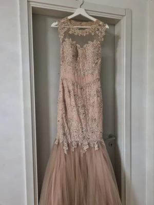 Klänning - Säljer en elegant långklänning i ljus rosa färg med vackra spetsdetaljer och blommig brodyr. Klänningen har en transparent övre del, hjärtformad urringning och ett voluminöst tyllparti nedtill. Perfekt för bal eller nyår. Dragkedja i ryggen och detaljerad spets över axlar och bröst. Klänningen är handmade i London. Jag köpte den för 2000 kr från angel forever. Jag hade på mid den bara en gång då jag bara testa den. Pris går att diskuteras vid snabbaffär.