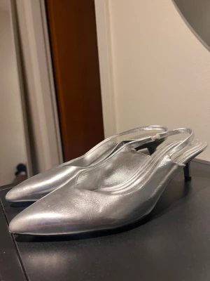 Silvriga pumps med spetsig tå kitten heel asos - Säljer ett par stilrena pumps i metallic silver med spetsig tå och låg klack. 