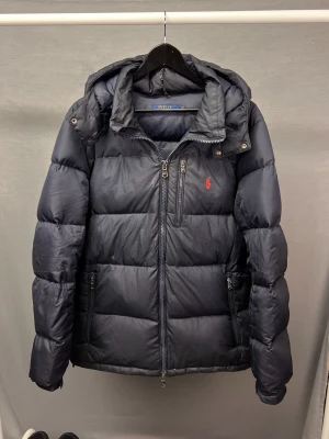 Ralph lauren jacka - Säljer denna sjukt snygga raffe jacka i size L! Kan även passa en M om du är mellan M och L! Skick 8/10 begagnad men bra skick utan hål eller skador! Avtagbar luva! Den är mörkblå! Såklart äkta! Hör av dig vid intresse 🤩🙌