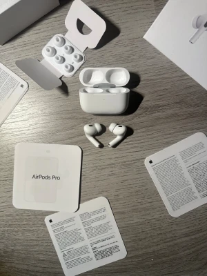 AirPods Pro (2nd Generation) med MagSafe-laddningsetui (USB-C) - Snygga AirPods Pro (2nd Gen) med MagSafe-laddningsetui och USB-C. Komplett med extra öronkuddar och originalförpackning. Aktiv brusreducering, transparensläge och hög ljudkvalitet. Små ytliga repor på etuiet, annars i mycket gott skick.