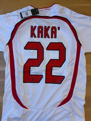 AC Milan Kaka Champions League tröja - Säljer en AC Milan matchtröja från Champions League-finalen 2007 med Kaka och nummer 22 på ryggen. Tröjan är vit med röda och svarta detaljer, broderat klubbmärke och Champions League-emblem, samt 'Rossoneri' broderat i nacken. Materialet är polyesters. Pris kan diskuteras vid snabb affär och skickar fort!