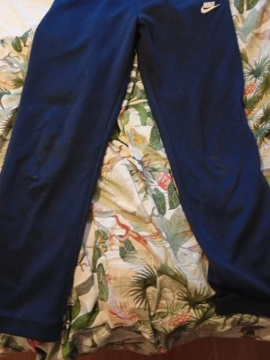 Mjukisbyxor från Nike Storlek 158-170 eller barn XL - Säljer ett par mörkblå mjukisbyxor från Nike i storlek barn XL, passar dig som är 158-170 cm. Byxorna har en enkel design med Nike-logga på höften och är gjorda i mjukt material som är skönt att ha på sig. Perfekta för chill eller träning.
