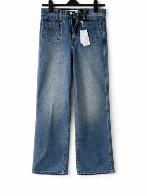 Blå wide leg jeans med hög midja - Säljer ett par blå jeans med wide leg och hög midja. Jeansen har klassiska fickor fram och raka ben. Perfekta för en avslappnad och trendig look. Materialet är kraftig denim i bomull.