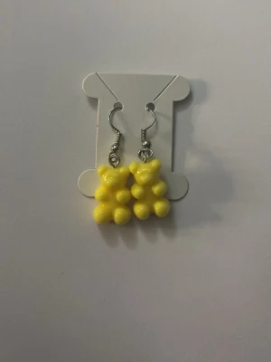 Gula örhängen med pärldetaljer - Snygga örhängen med hängande gula pärlor formade som björnar. Krokar i metall och lekfull design som sticker ut. Perfekta för dig som gillar färgglada accessoarer och unika smycken.