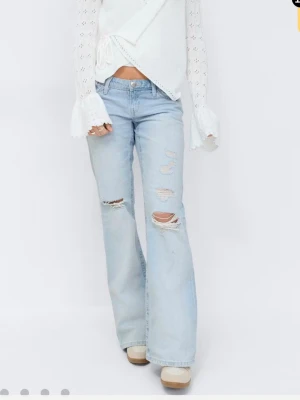 Ljusblå slitna bootcut jeans - Säljer ett par ljusblå bootcut jeans med slitningar och hål på framsidan. Säljer för att det är för stora i midjan samt lite för korta i längden på mig som är 176! 