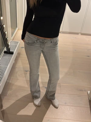 Ljusgrå bootcut jeans - Säljer ett par ljusgrå bootcut jeans med snygga fickdetaljer bak och klassisk femficksmodell. Jeansen har låg midja och är i stretchigt denimtyg som sitter skönt. Perfekta till en trendig vardagslook.