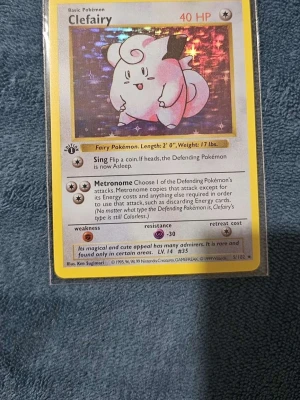 Pokémonkort Clefairy 1st Edition  - Säljer ett Clefairy-kort från Pokémon Base Set. Kortet har holografisk yta och visar Clefairy, en rosa och vit älvliknande figur. Kortet har 40 HP och innehåller attackerna Sing och Metronome. Perfekt för samlare eller Pokémonfans!