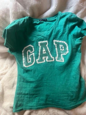 Grön/turkos GAP t-shirt med stor logga - En så söt grön t-shirt från GAP, en enkel t shirt och stilren design, älskar färgen och allt men har tyvärr inte funnit användning för den. Den är i barn storlek XL så den funkar ungefär som en vanlig S.