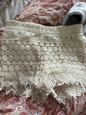 Vita spetsiga shorts med blommönster - Superfina vita shorts med blommig spets och volangkant. Säljer då dom är för små 