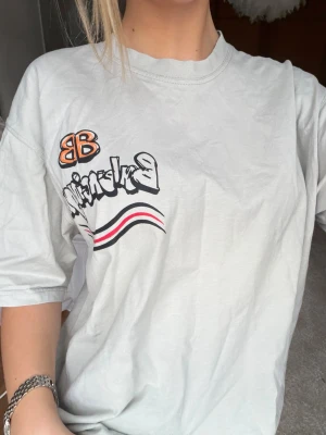 Balenciaga t-shirt med graffiti - Super cool vit/ljus grå t-shirt från Balenciaga med graffiti logga. Sitter oversized på mig som bär S
