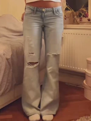 Ljusblåa bootcut jeans - Säljer ett par ljusblåa bootcut jeans med slitna detaljer på låren och knäna. Dom är från Gina och är slutsålda, längd petite. Helt nya i orginalförpaknig med lappen kvar.