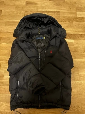 Svart pufferjacka från Polo Ralph Lauren - Riktig fräsch svart Ralph lauren puffer jacka, som är perfekt för vintern. Den är fräsch, men dock så tappar det dun inuti jackan. Hör av er vid funderingar! Pris kan diskuteras! 