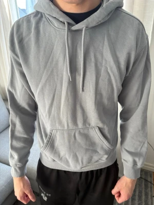 Herr ljusblå hoodie med magficka - En stilren ljusblå hoodie med huva och dragsnören. Hoodien har en klassisk känguruficka framtill och ribbade muddar vid ärmslut och midja. Den kommer från H&M och är i storlek XS.       Killen är 180cm.