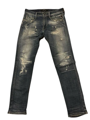 Blå slitna replay anbass jeans  - Snygga blå jeans från replay med slitningar och distressed detaljer framtill. Raka ben och klassisk femficksmodell. Perfekta för en avslappnad och trendig look. Hör av er vid fler frågor.