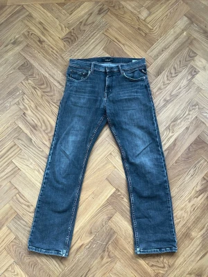Replay svarta jeans straight fit - Säljer ett par svarta Replay jeans med klassisk femficksdesign och raka ben. Jeansen har en diskret tvättad look och tydliga sömmar på bakfickorna. Materialet är mjukt och stretchigt för komfort. Jeansen passar perfekt till en person som är mellan 160-175 cm.