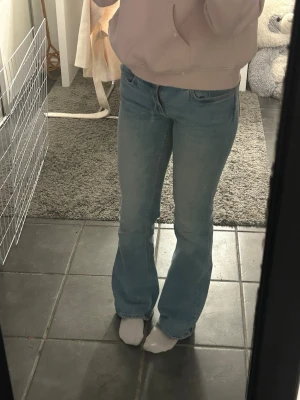 Ljusblå bootcut jeans - Säljer ett par ljusblå bootcut jeans med klassisk femficksdesign och normal midja. Jeansen har en avslappnad passform över låren och lätt utsvängda ben. Perfekta för en chill och trendig look.