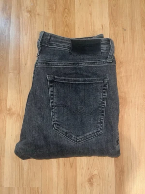 Jack & Jones  - Snygga gråa jeans i tvätt från Jack & Jones, modell Skinny / Liam. Midja 38cm, längd 100cm. JAG SKICKAR EJ FLER BILDER NÄR JAG BÄR JEANSEN! för bättre inblick i passformen rekommenderar jag att googla på modellnamnet. För storleksguide kolla måtten noggrant då jeansen alltid kan vara uppsydda heller krympta och jag ej tar emot returer :) 