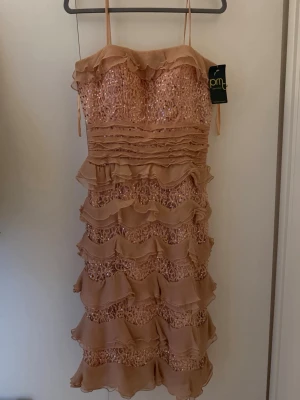 Glittrig klänning från PM/permotex - Helt ny klänning med prislapp kvar, aldrig använd. Långklänning/bal Glittrig med volanger.          Storlek 42/L 