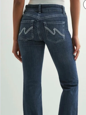 Nelly jeans! - Snygga mörkblå bootcut jeans från Nelly med kontrastsömmar och ikoniska bakfickor med zigzag-mönster. Jeansen har normal midja, klassisk femficksdesign och är tillverkade i stretchig denim för skön passform.💗💗