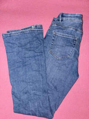 Blå jeans från Vero Moda - Snygga blå jeans från Vero Moda normal/ lite lägre midja. Jeansen har en lätt tvättad look och boot cut. Väldigt stretchiga och mjuka. Har en slitning på ena benet som ska vara design, alltså ingen defekt. Använda väldigt få gånger