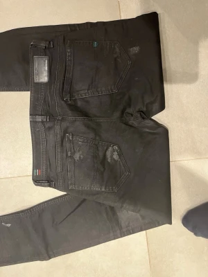 Svarta slim jeans från Diesel - Säljer ett par svarta slim fit jeans från Diesel, modell D-ALA FWY2015. Jeansen har klassisk femficksdesign, diskreta slitningar och detaljer i svart. Materialet är stretchigt för extra komfort och passform. Perfekta för en trendig och avslappnad look.