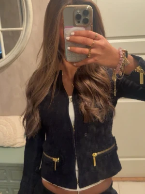 Mörkblå kort zip-jacka med guld-dragkedjor - Snygg mörkblå kort cardigan med dragkedja framtill och två guldfärgade dragkedjor på fickorna. Figurnära passform och långa ärmar. Perfekt att styla över ett linne eller t-Shirt. Den är från michel kors och för liten för mig. Skulle säga att det är lite liten i storleken. Knappt använd.